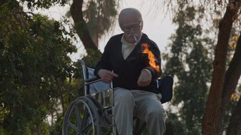 Movie still from “Jackass 4.5” (2022), directed by Jeff Tremaine – An old man sitting in a wheel chair smoking a cigarette; Medium shot, Low angle