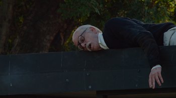 Movie still from “Jackass 4.5” (2022), directed by Jeff Tremaine – An old man with glasses is laying on a bench; Medium shot, Low angle