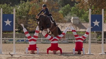 Movie still from “Jackass 4.5” (2022), directed by Jeff Tremaine – A person on a horse jumping over a group of people on the ground; Wide shot, Low angle