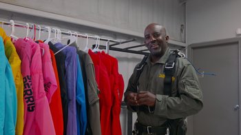 Movie still from “Jackass 4.5” (2022), directed by Jeff Tremaine – A man standing in front of a rack of clothes; Medium shot, Low angle