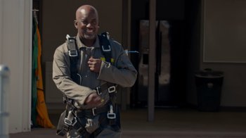 Movie still from “Jackass 4.5” (2022), directed by Jeff Tremaine – A man in a harness smiles for the camera; Medium shot, Low angle