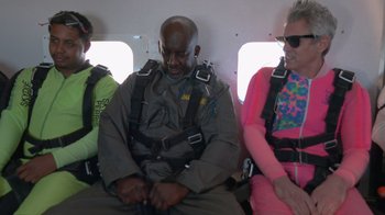 Movie still from “Jackass 4.5” (2022), directed by Jeff Tremaine – A man and two women sitting on a plane wearing parachutists; Medium shot, Low angle