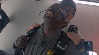 Movie still from “Jackass 4.5” (2022), directed by Jeff Tremaine – A police officer is hugging a man in a uniform; Close Up shot, Overhead angle