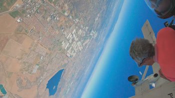 Movie still from “Jackass 4.5” (2022), directed by Jeff Tremaine – A person is looking out a window of a plane; Wide shot, Overhead angle