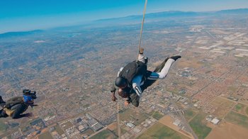 Movie still from “Jackass 4.5” (2022), directed by Jeff Tremaine – A skydiver is in the air over a city; Extreme Wide shot, Low angle