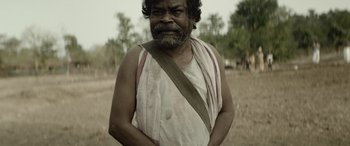Movie still from “Jawan” (2023), directed by Atlee – An old man with a beard and a white shirt is posing for a picture; Close Up shot, Low angle