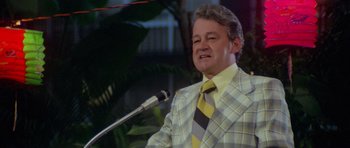 Movie still from “Jaws 2” (1978), directed by Jeannot Szwarc – A man wearing a suit and tie while speaking into a microphone; Medium shot, Low angle