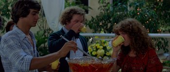 Movie still from “Jaws 2” (1978), directed by Jeannot Szwarc – A man in a bow tie is eating a banana; Medium shot, Low angle