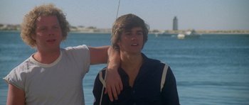 Movie still from “Jaws 2” (1978), directed by Jeannot Szwarc – A man standing next to another man near the water; Close Up shot, Low angle