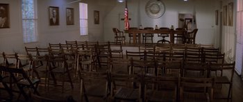 Movie still from “Jaws 2” (1978), directed by Jeannot Szwarc – A room filled with wooden chairs next to a table; Extreme Wide shot, High angle
