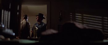 Movie still from “Jaws 2” (1978), directed by Jeannot Szwarc – A man wearing a cowboy hat standing in a dark room; Wide shot, Over the shoulder angle