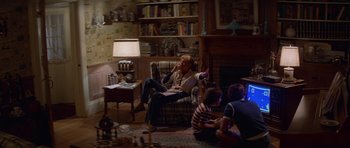 Movie still from “Jaws 2” (1978), directed by Jeannot Szwarc – A woman sitting in a chair in front of a fire place; Wide shot, High angle