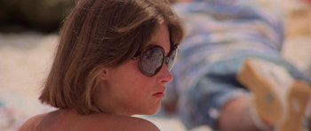 Movie still from “Jaws 2” (1978), directed by Jeannot Szwarc – A young girl wearing a pair of round sunglasses; Close Up shot, High angle