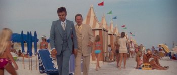 Movie still from “Jaws 2” (1978), directed by Jeannot Szwarc – A man in a suit standing next to another man in a tan suit; Wide shot, Low angle