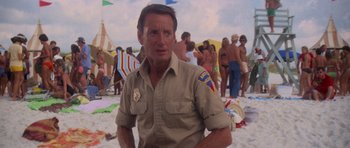 Movie still from “Jaws 2” (1978), directed by Jeannot Szwarc – A man standing on the beach with a group of people in the background; Medium shot, Low angle