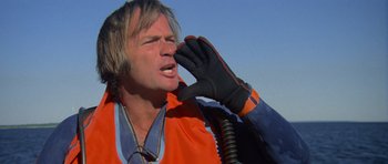 Movie still from “Jaws 2” (1978), directed by Jeannot Szwarc – A man in an orange vest talking on a phone; Close Up shot, Low angle