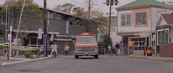 Movie still from “Jaws 2” (1978), directed by Jeannot Szwarc – An ambulance driving down a street with people walking around; Wide shot, Low angle