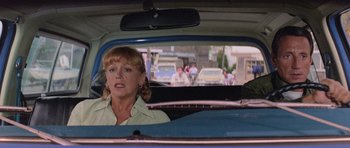 Movie still from “Jaws 2” (1978), directed by Jeannot Szwarc – A woman sitting in the back seat of a car looking out the window; Medium shot, Over the shoulder angle