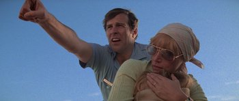 Movie still from “Jaws 2” (1978), directed by Jeannot Szwarc – A man and a woman standing next to each other in front of a blue sky; Close Up shot, Low angle