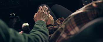 Movie still from “Jeepers Creepers: Reborn” (2022), directed by Timo Vuorensola – Two people holding their hands in a car seat; Extreme Close Up shot, High angle
