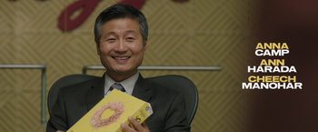 Movie still from “Jerry and Marge Go Large” (2022), directed by David Frankel – A man sitting in a chair holding a box of donuts; Close Up shot, Over the shoulder angle