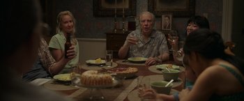 Movie still from “Jerry and Marge Go Large” (2022), directed by David Frankel – A group of people sitting around a table with plates of food; Medium shot, Over the shoulder angle