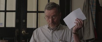 Movie still from “Jerry and Marge Go Large” (2022), directed by David Frankel – An older man wearing glasses is holding a pen and paper; Close Up shot, Over the shoulder angle