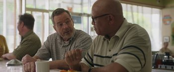 Movie still from “Jerry and Marge Go Large” (2022), directed by David Frankel – Two men sitting at a table talking to each other; Close Up shot, Over the shoulder angle