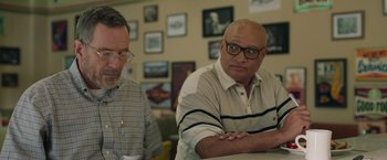 Movie still from “Jerry and Marge Go Large” (2022), directed by David Frankel – Two men sitting at a table in front of each other; Medium shot, Over the shoulder angle