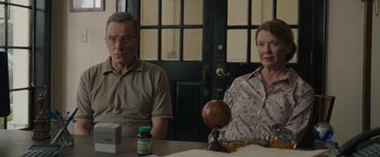 Movie still from “Jerry and Marge Go Large” (2022), directed by David Frankel – A man and a woman sitting at a wooden table; Medium shot, Low angle