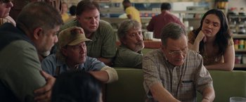 Movie still from “Jerry and Marge Go Large” (2022), directed by David Frankel – A group of men sitting on a bench in a restaurant; Medium shot, Over the shoulder angle