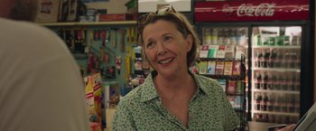 Movie still from “Jerry and Marge Go Large” (2022), directed by David Frankel – A woman in a green shirt is smiling for the camera; Close Up shot, Over the shoulder angle