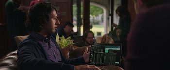 Movie still from “Jerry and Marge Go Large” (2022), directed by David Frankel – A man sitting on a couch with a laptop; Medium shot, Over the shoulder angle