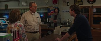 Movie still from “Jerry and Marge Go Large” (2022), directed by David Frankel – Two men and a woman standing at a counter; Medium shot, Over the shoulder angle