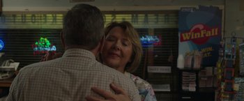Movie still from “Jerry and Marge Go Large” (2022), directed by David Frankel – An older man and woman hugging in front of a news sign; Close Up shot, Over the shoulder angle