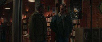 Movie still from “Jerry and Marge Go Large” (2022), directed by David Frankel – Two men standing next to each other in front of a bookcase; Medium shot, Over the shoulder angle