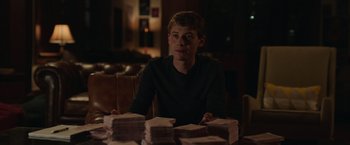 Movie still from “Jerry and Marge Go Large” (2022), directed by David Frankel – A man sitting in front of a pile of papers; Medium shot, Over the shoulder angle