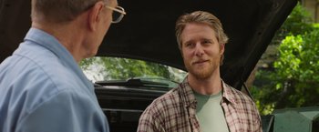 Movie still from “Jerry and Marge Go Large” (2022), directed by David Frankel – A man in a plaid shirt talking to another man in a car; Close Up shot, Over the shoulder angle