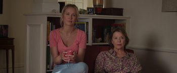 Movie still from “Jerry and Marge Go Large” (2022), directed by David Frankel – Two women are sitting on a couch and one is holding a cup; Medium shot, Over the shoulder angle