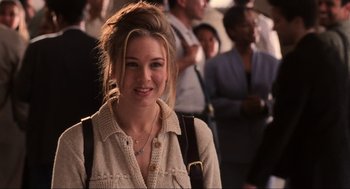 Movie still from “Jerry Maguire” (1996), directed by Cameron Crowe – A beautiful young lady smiling for the camera while standing in a crowd of onlookers; Close Up shot, Over the shoulder angle