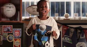 Movie still from “Jerry Maguire” (1996), directed by Cameron Crowe – A young boy is holding a soccer ball and a bat; Medium shot, Low angle