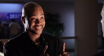 Movie still from “Jerry Maguire” (1996), directed by Cameron Crowe – A man with a shaved head smiling for the camera; Close Up shot, Low angle