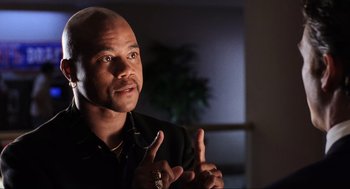 Movie still from “Jerry Maguire” (1996), directed by Cameron Crowe – A man with a bald head talking to someone in a dark room; Close Up shot, Low angle