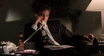 Movie still from “Jerry Maguire” (1996), directed by Cameron Crowe – A man sitting at a table talking on a phone; Medium shot, High angle
