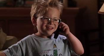 Movie still from “Jerry Maguire” (1996), directed by Cameron Crowe – A young boy wearing glasses talking on a cell phone; Close Up shot, High angle
