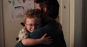Movie still from “Jerry Maguire” (1996), directed by Cameron Crowe – A man hugging a young boy with glasses on; Close Up shot, Over the shoulder angle