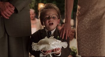 Movie still from “Jerry Maguire” (1996), directed by Cameron Crowe – A little boy in a suit holding a wedding cake; Close Up shot, Over the shoulder angle