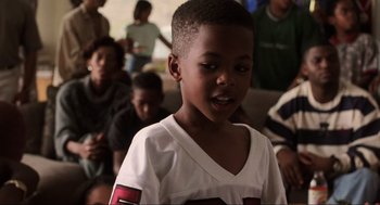 Movie still from “Jerry Maguire” (1996), directed by Cameron Crowe – A little boy that is standing in front of a group of people; Close Up shot, Over the shoulder angle