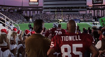 Movie still from “Jerry Maguire” (1996), directed by Cameron Crowe – A group of people watching a football game in a stadium; Extreme Wide shot, High angle