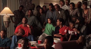Movie still from “Jerry Maguire” (1996), directed by Cameron Crowe – A group of people sitting in a living room watching a football game; Medium shot, High angle